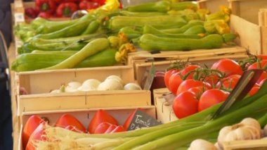 Fransız çiftçi pazarında tahta sandıklarda sergilenen taze kabaklı, soğanlı ve domatesli kabak. Tabelada Fransızcada küçük bir etiket görünür. Yerel üretim ve Akdeniz mutfağı kavramı