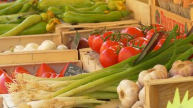 Nice, Fransa - 10 Eylül 2025: Fransız çiftçi pazarında ahşap sandıklarda sergilenen taze kabak, soğan ve domateslerle yakın plan. Tabelada Fransızcada küçük bir etiket görünür. Yerel üretim ve Akdeniz kavramı