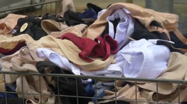 Açık hava pazarında tel bir sepetin içinde bej, kırmızı, beyaz ve siyah renkli sutyenler de dahil olmak üzere çeşitli kadın iç çamaşırlarının yakın çekimleri. İkinci el giyim veya bütçe perakende konseptini temsil eder.