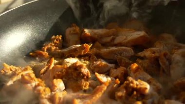 Tavada kızartılmış altın sarısı etin detaylı görüntüsü. Yemek hazırlıkları sırasında sıcak mutfak ışığında buhar yükseliyor.