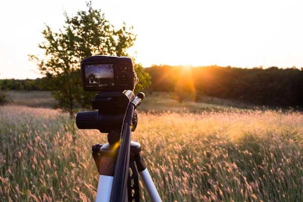 Tipo de câmera que dispara o pôr do sol em um tripé — Fotografia de Stock