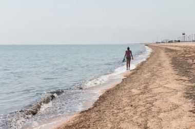 Güzel kız deniz kıyısında yürüyüş