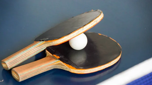 Rackets and ball on the blue tennis table. Indoor sport activity. Sport concept.