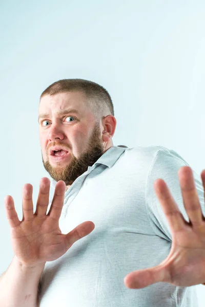 Sakallı bir adam korkar ve ellerini öne uzatır.