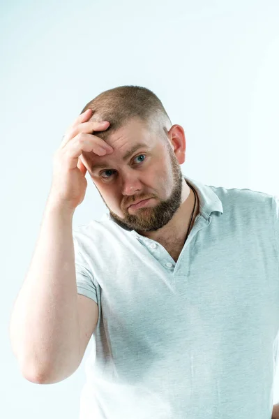 Sakallı, güzel bir adam elini kafasında tutuyor.