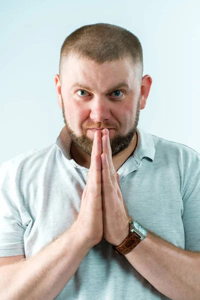 Bir adam ellerini kavuşturup çerçeveye bakar..