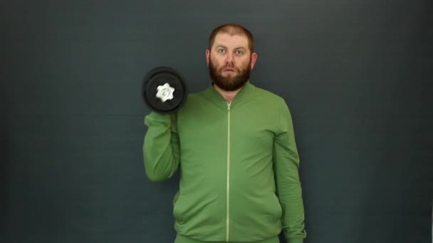 A man in a tracksuit lifts a heavy dumbbell with one hand — Stock Video