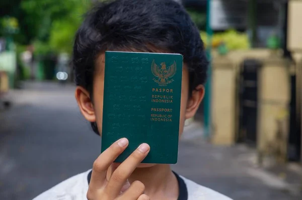Endonezyalı çocuk Endonezya Cumhuriyeti pasaportunu gözünün önünde tutuyor, seçilmiş odak noktası.