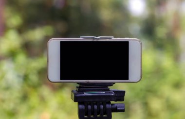 A mobile phone mounted on a tripod capturing image of natural forest in Wonogiri, Indonesia.