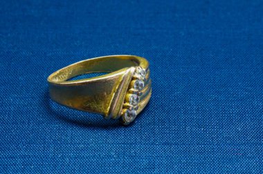 Mavi bir paspasın üzerinde değerli taşlar olan, seçilmiş bir altın yüzük.