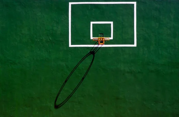 Yeşil beton duvarında gölgesi olan basketbol yüzüğü.