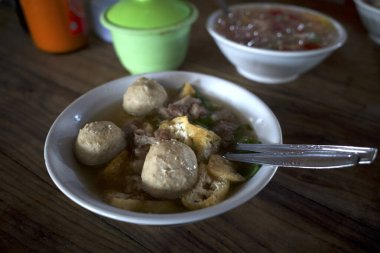 Bir kase köfte çorbası, eski ahşap masada taze sebzeli Bakso..