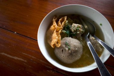 Bir kase köfte çorbası, eski ahşap masada taze sebzeli Bakso..