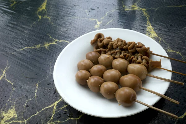 İç organlar ve bıldırcın yumurtaları beyaz bir tabakta satay, Endonezya Yogyakarta 'da lezzetli sokak yemekleri.