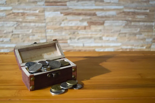 Angle view of chest box with coins on the table. Saving concept