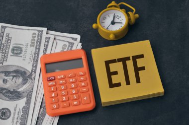 ETF ile yazılan para banknotları, hesap makinesi, saat ve not seçici odak EXCHANGE TRADED