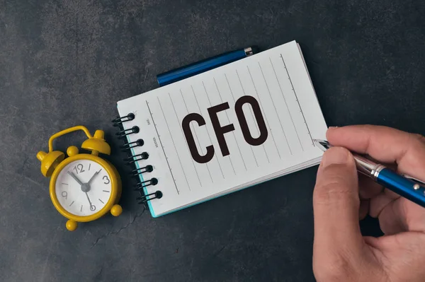 Top view of man hand holding pen and writing CFO stands for Chief Financial Officer