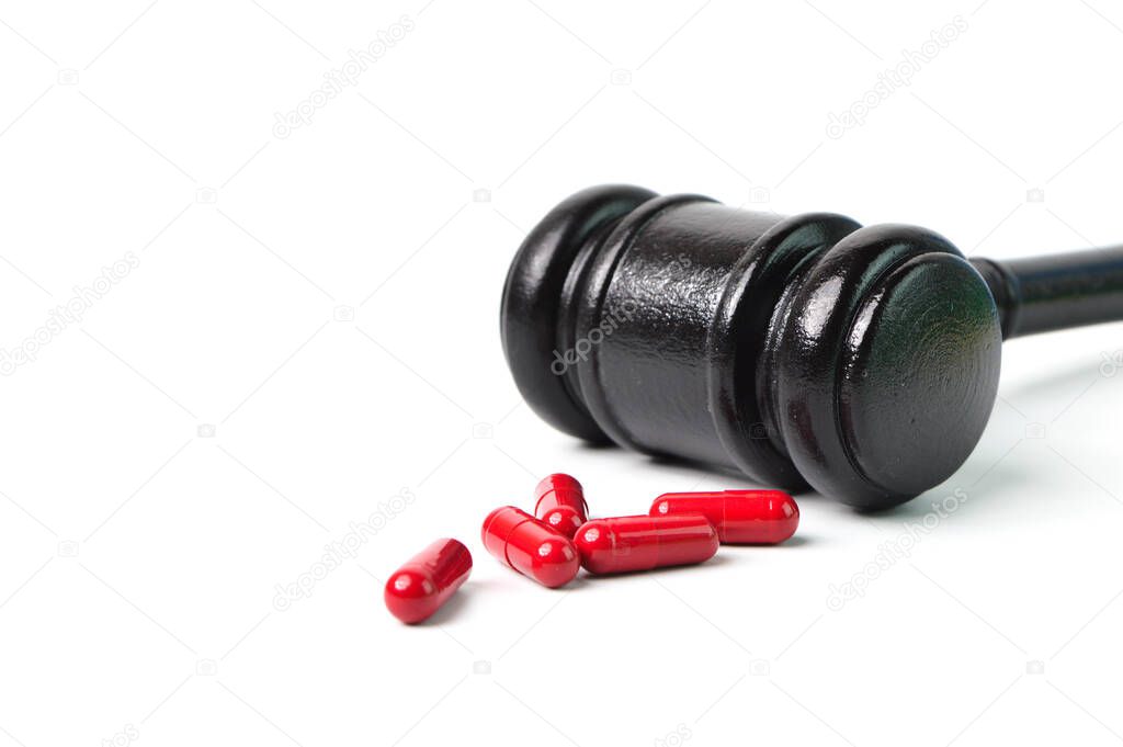 Pill capsules and judge hammer over white background