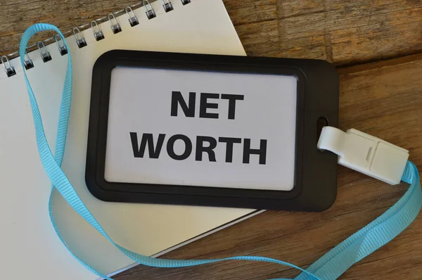 Notebook and name tag written with text NET WORTH.