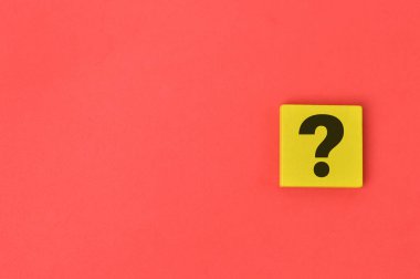 Kırmızı arkaplan üzerine tahta blok üzerine soru işareti çizildi.