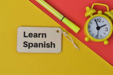 Saat, kalem ve tahta etiket LeARN SPANISH ile yazılmış.