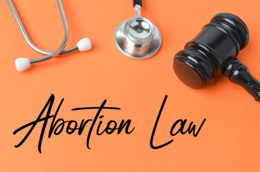 Yargıç Tokmak, steteskop turuncu arkaplan üzerinde ABORTION Kanunu ile yazılmış.