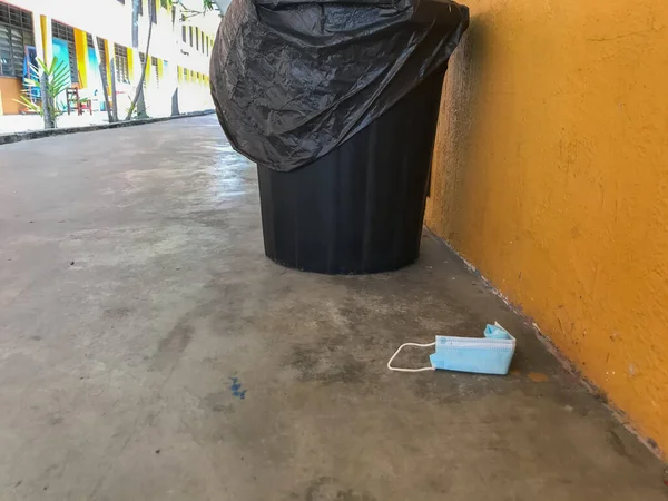 Face mask on the floor beside the dustbin