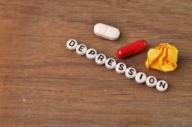 İlaç kapsülleri, kağıt atıkları ve metin depresifli alfabe boncukları.