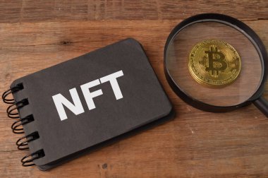 Golden bitcoin and note book written with NFT stands for NON FUNGIBLE TOKENS clipart
