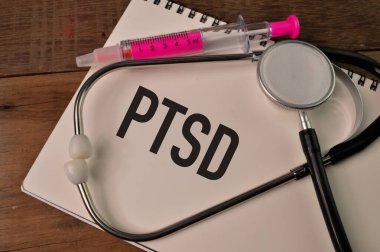 Stetoskop, şırınga ve PTSD ile yazılmış not defteri Travma Sonrası Stres Bozukluğu anlamına geliyor.