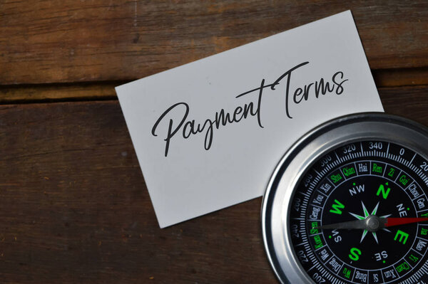Top view of compass and memo note written with PAYMENT TERMS. A business concept