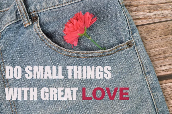 Phrase DO SMALL THINGS WITH GREAT LOVE written on blue jeans with flower