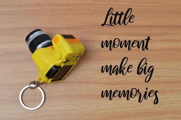 Phrase LITTLE MOMENT MAKE BIG MEMORIES written on wooden table.