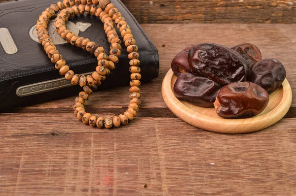 Bunch of dates, Islamic prayer beads and holy quran on wooden board with copy space. Ramadan kareem festive