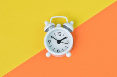 Sarı ve turuncu arkaplanda beyaz saatin üst görünümü