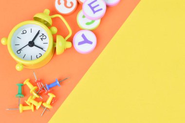 Saatin üst görüntüsü, alfabe harfleri ve pim tahtaları sarı ve turuncu arkaplanlarda izole edilmiş ve fotokopi alanı var. Eğitim kavramı