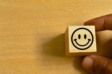 Adam ahşap blokla el ele tutuşuyor mutlu bir gülümsemeyle ahşap arka planda duygu var.