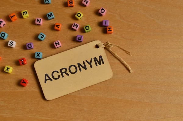 用Acronym编写的彩色字母表珠和标签的顶部视图 — 图库照片