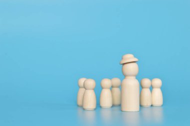 Mavi arka planda izole edilmiş, lider ve ofis çalışanlarının tahta bebek figürü.