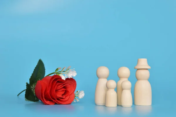 Wooden doll figures and red flower on isolated on a blue background