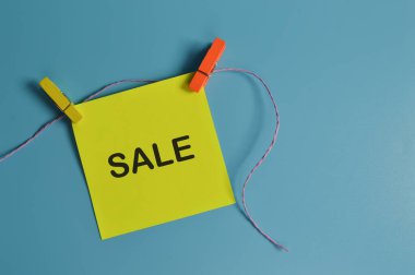 Mavi arkaplanda SALE ile yazılmış kağıt notun üst görünümü