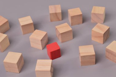 Grubun tahta bloklarından sarkan kırmızı tahta küp blok. Muhalif görüş ve liderlik kavramı.