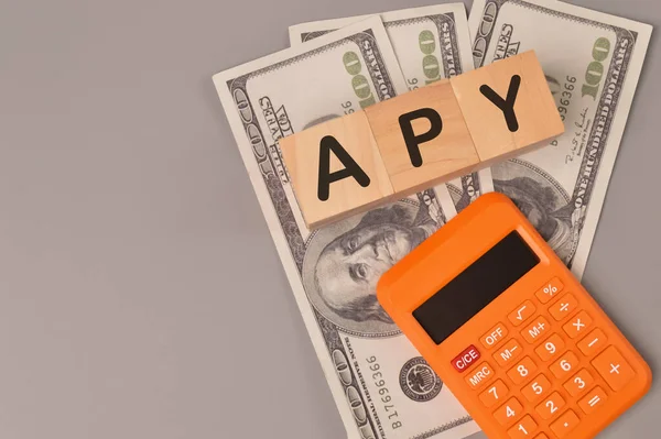 Para banknotları, hesap makinesi ve APY ile yazılmış tahta blokların üst görünümü YILLIK PERCENTAGE YIELD