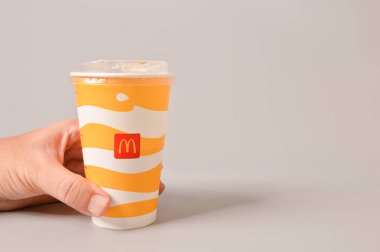 Klang, Malezya: 24 Haziran 2021 McDonald 's meşrubatını gri arka planda izole edilmiş kağıt bardakta tutuyor. Boşluğu kopyala.