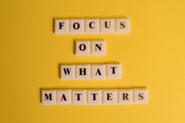 Square letters with text FOCUS ON WHAT MATTERS isolated on yellow background.