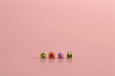 Renkli alfabe boncukları ve pembe arka planda izole CALM metni