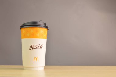 Klang, Malezya: 25 Temmuz 2021 - McKafe kahve fincanı, gri arka planda izole edilmiş ahşap masa üzerinde