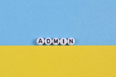 Alphabet beads with text ADMIN isolated on blue and yellow background