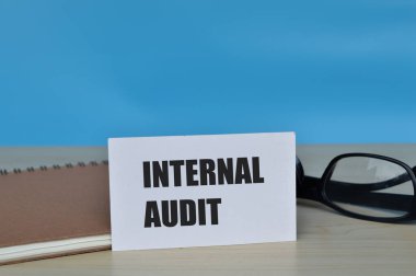 Gözlük, kitap ve beyaz kartın ön görünümü InterTERNAL AUDIT ifadesiyle yazıldı