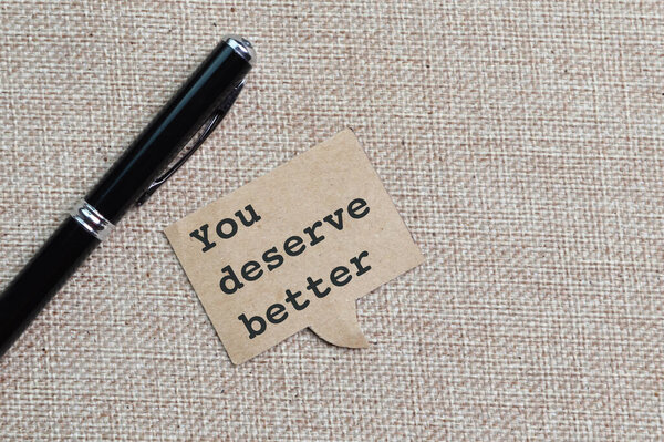 Pen and speech bubble note written with text YOU DESERVE BETTER